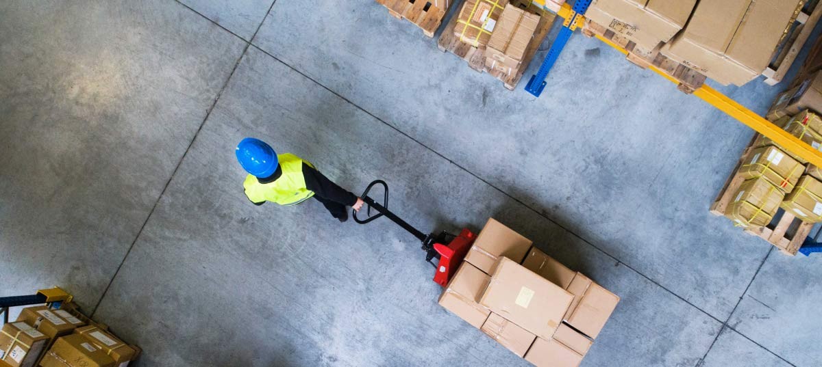 Logistic worker pulling the carton boxes in the warehouse