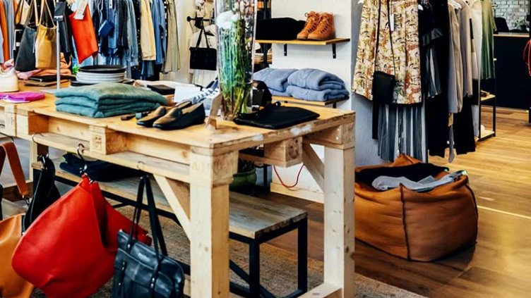 A clothing store showcasing a variety of garments and bags elegantly arranged for display.