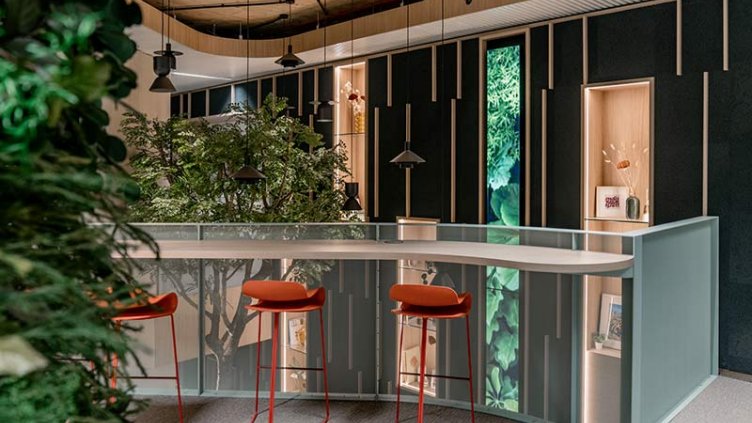 Modern office space with curved counter, red stools, plants, wood accents