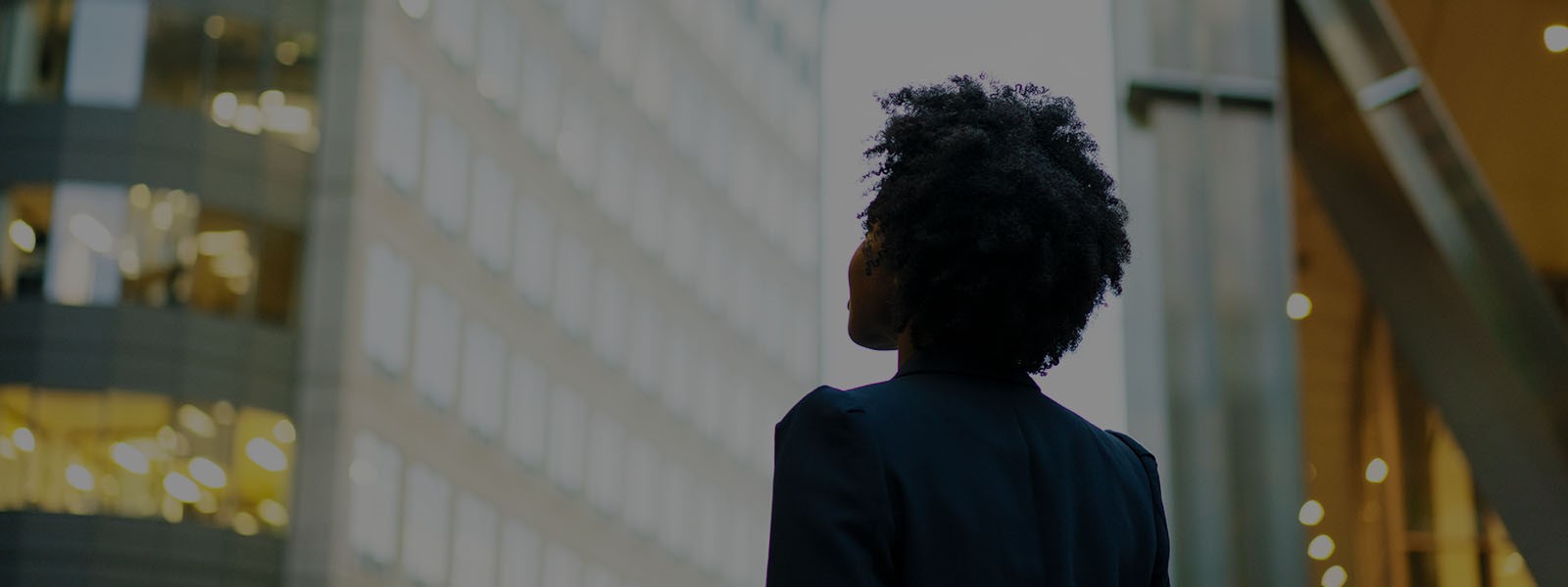 A lady looking towards the high rise real estate office glass building