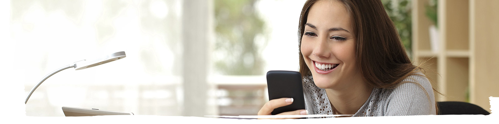 A female is looking at her mobile and smiling