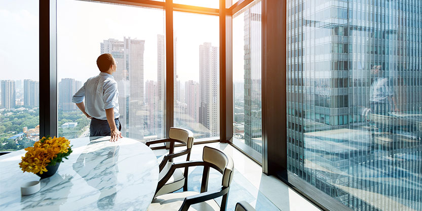 Man looks out of window at buildings