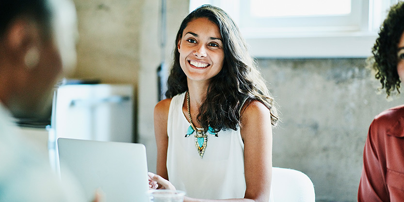 Smiling businesswoman in discussion with colleagues during meeting in office conference room