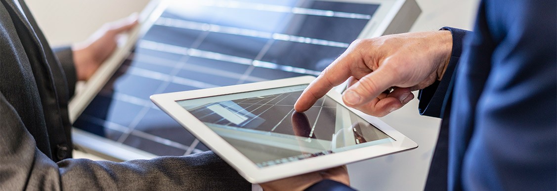 Close-up of two businessmen in office with solar cell and tablet