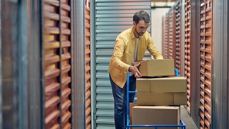 Man loading boxes from a trolley into a self storage unit.