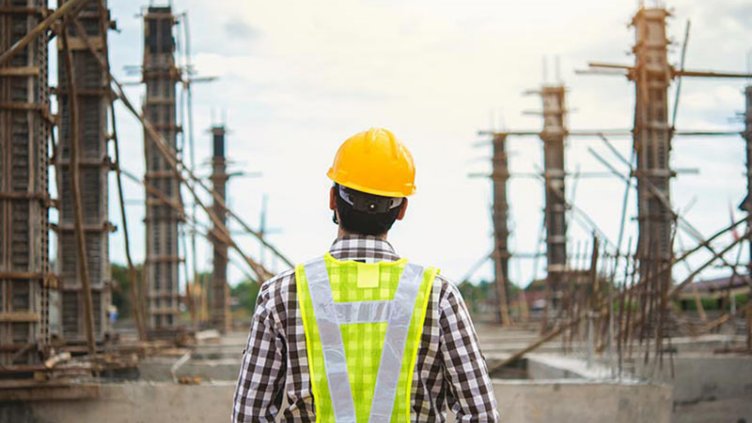 A worker in front of a construction site